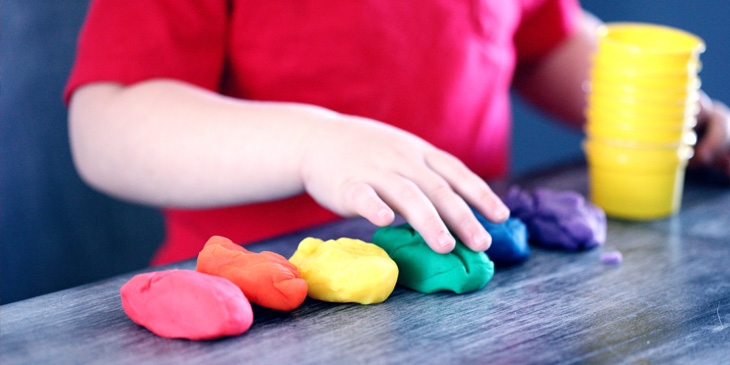 A child playing with different coloured piles of Play-Doh