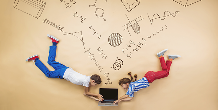 Two children photographed from above typing on a laptop with maths flowing from it