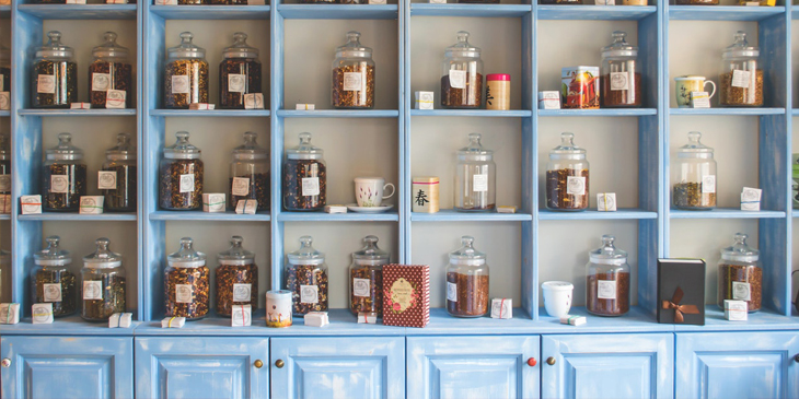 A large set of shelves, full of numerous jars filled with tea leaves
