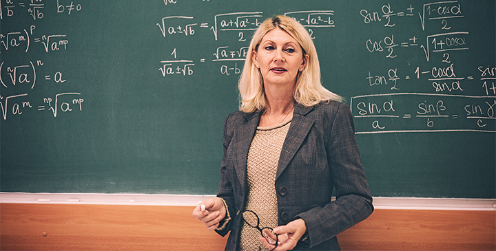A Maths teacher in front of a blackboard