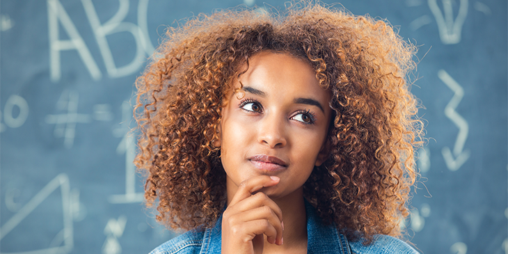 A young woman in thoughtful pose in front of a blackboard