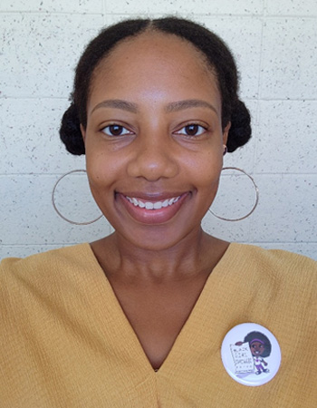 Photo of Dr. Keisha Cook wearing a yellow top with a white badge