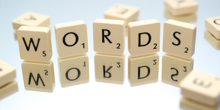 Five scrabble pieces upright spelling the word Words