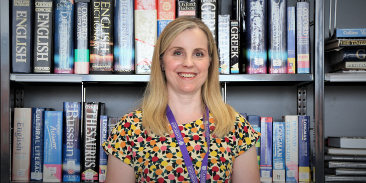 A headshot of Carrie in-front of a bookcase full of books