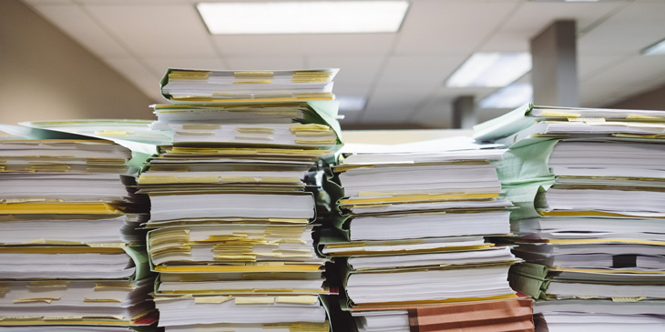 Four piles of folders filled with papers, with post-it notes sticking out