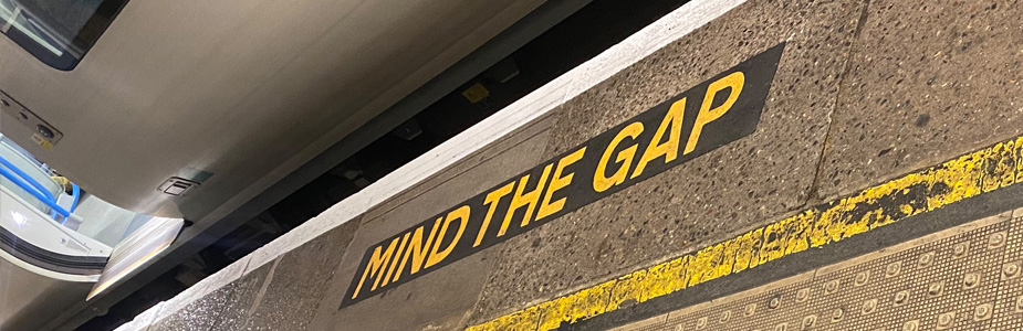 Close up of the words 'Mind the gap' painting on the floor near a tube train at a station platform