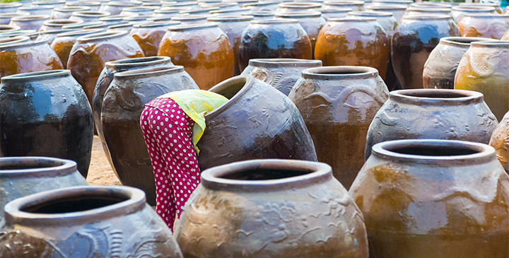 A collection of large pots with a young girl climbing into one