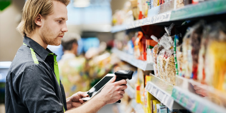 A man working retail, using a scanner to scan an item on the shelf