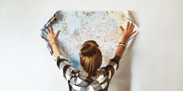 A person holding up a printed map of europe against a wall