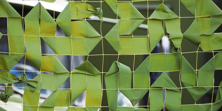 Green fabric arranged in patterns through a rope net