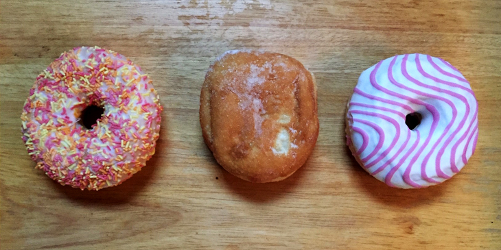 Three different types of doughnuts placed on a wooden surface