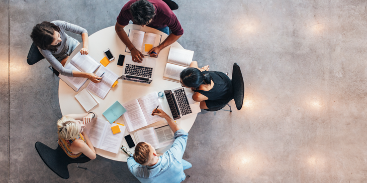 Top view of group of people sitting together at table learning