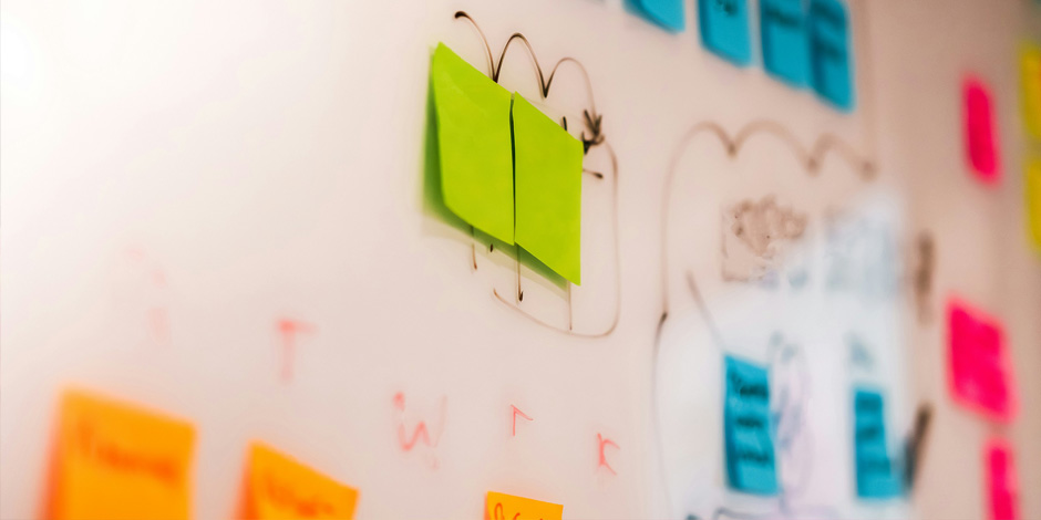 A white board with different coloured post-it notes on