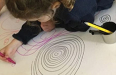 A child drawing spirals on a sheet of paper
