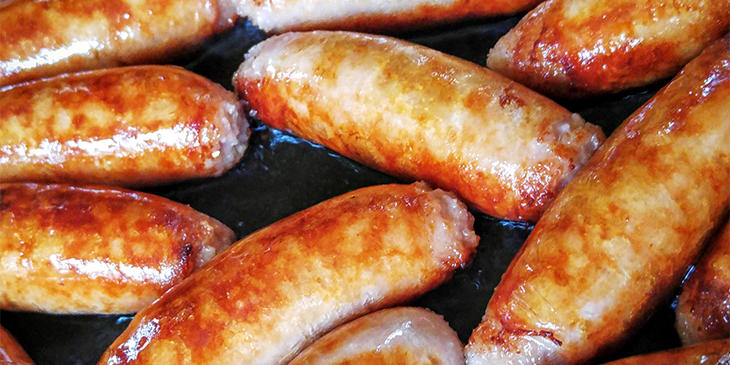 A bunch of sausages frying on a pan