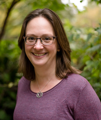 A headshot of Sophie Carr, in-front of a natural backdrop