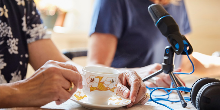 Midsection of two women having coffee while podcasting