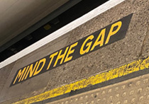 Close up of the words 'Mind the gap' painting on the floor near a tube train at a station platform