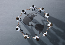 Group of children photographed from above on a tarmac surface with a globe painted on the ground inbetween them
