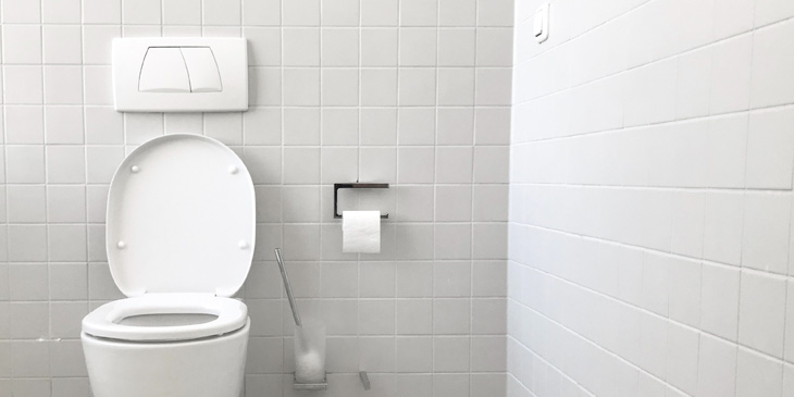 A toilet with push buttons of two different sizes, in a tiled room