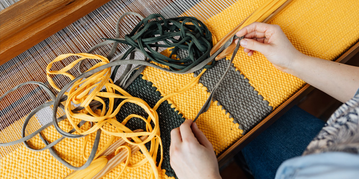 Someone weaving a large crochet in black and yellow yarn